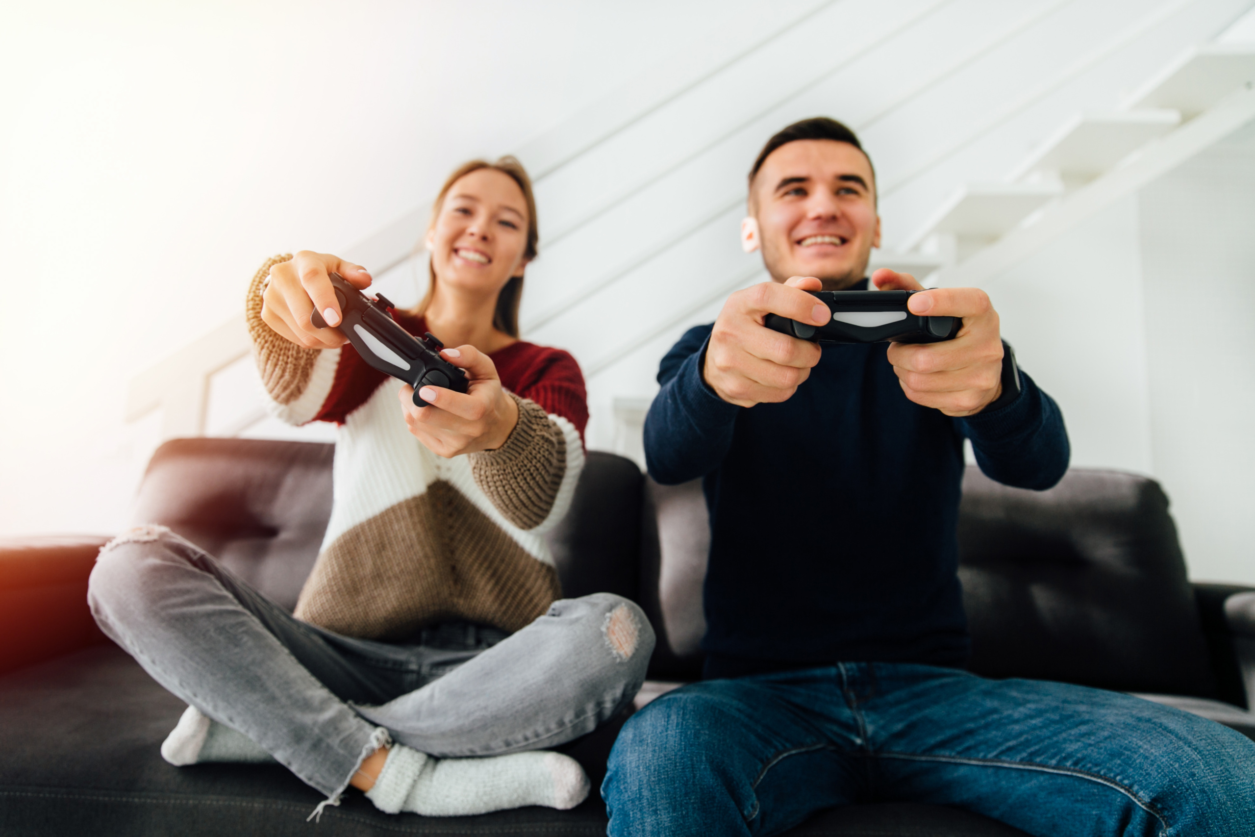 Smiling girl and guy playing video games using joysticks